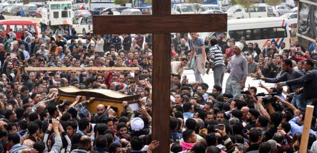 Mourners carry a large cross and the coffin of one of the victims of the blast at the Coptic Christian Saint Mark's church (Photo credit: MOHAMED EL-SHAHED/AFP/Getty Images)