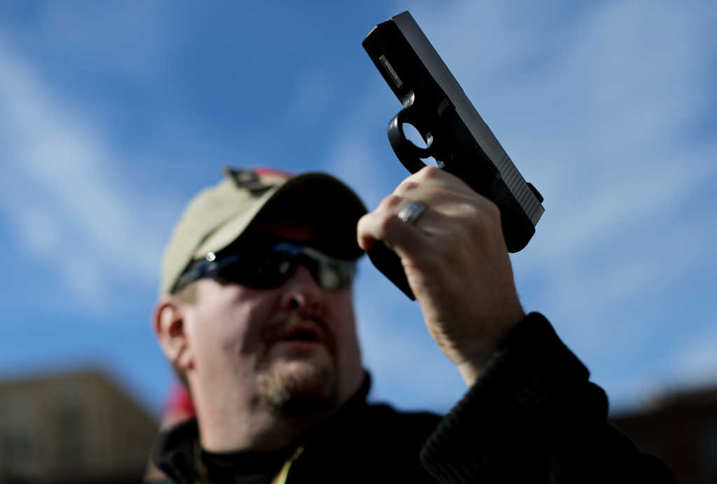 DALLAS, TX - JANUARY 19: Second Amendment supporter and gun enthusiast Derek Ringley displays an unloaded pistol that was being sold in an impromptu auction across the street from a gun buy back program at the First Presbyterian Church of Dallas on January 19, 2013 in Dallas, Texas. U.S. President Barack Obama recently unveiled a package of gun control proposals that include universal background checks and bans on assault weapons and high-capacity magazines. (Photo by Tom Pennington/Getty Images)