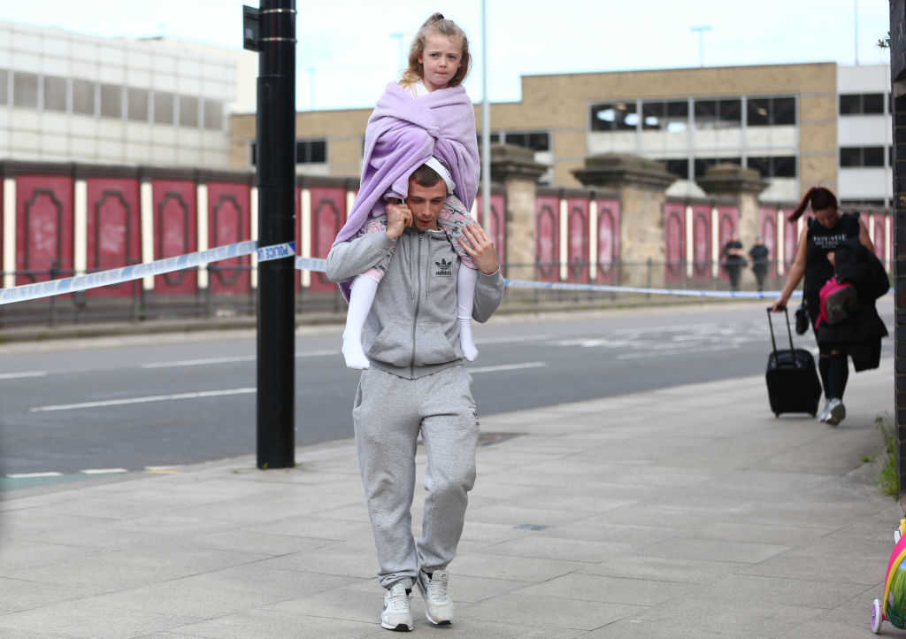 MANCHESTER, ENGLAND - MAY 23: A man carries a young girl on his shoulders on May 23, 2017 in Manchester, England. An explosion occurred at Manchester Arena as concert goers were leaving the venue after Ariana Grande had performed. Greater Manchester Police are treating the explosion as a terrorist attack and have confirmed 22 fatalities and 59 injured. (Photo by Dave Thompson/Getty Images)