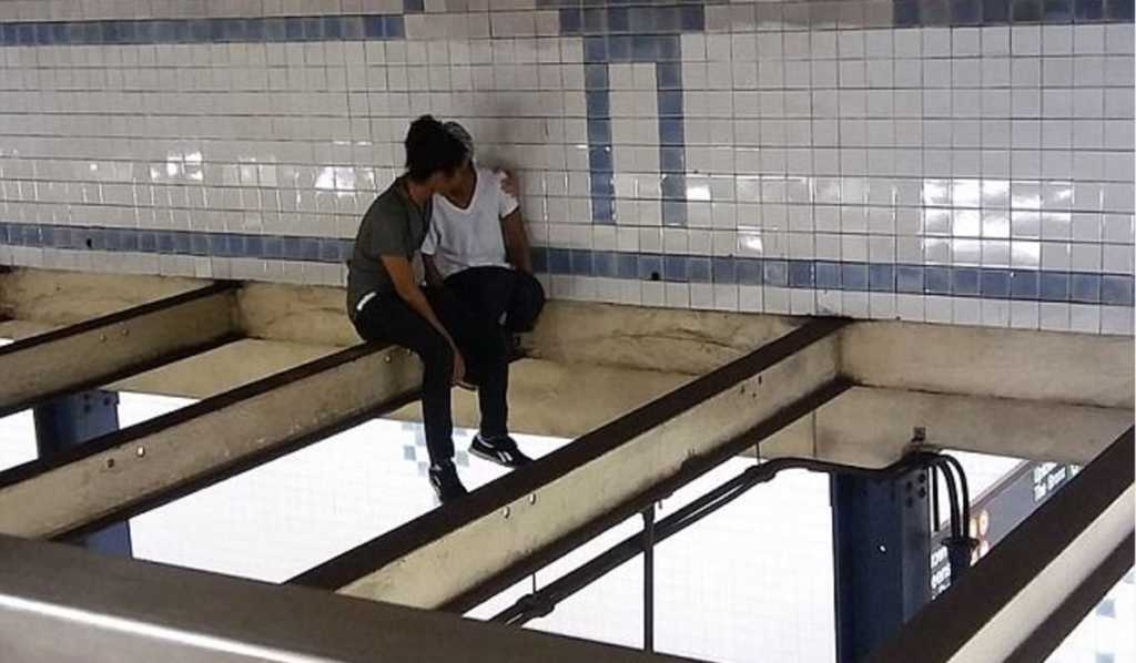 A man comforts a suicidal woman above NYC subway tracks. (Photo Credit: Michal Klein/Facebook)